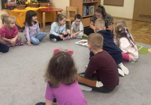 Dzieci z zaciekawieniem słuchają bajki.