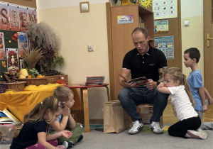 Dziewczynka opiera się o kolana swojego taty.