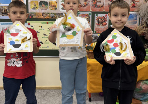 Chłopcy prezentują swoje prace - karmniki z ptakami w środku.