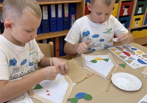 Chłopcy układają i przyklejają części ptaka.