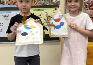 Chłopiec i dziewczynka pokazują wykonane prace.