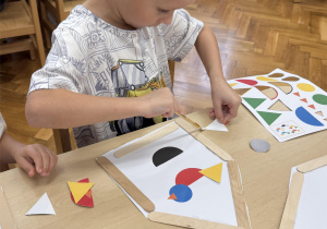 Chłopiec komponuje obrazek ptaka z różnych części.