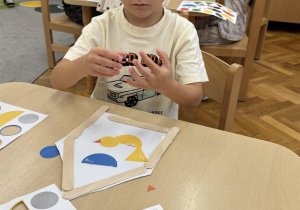 Chłopiec składa ptaka z kolorowych elementów.