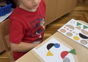 Chłopiec układa ptaki z papieru.