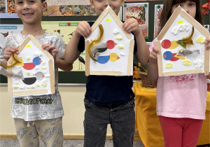 Dzieci z dumą prezentją wykonane przez siebie karmniki.