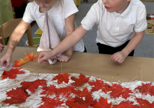 Chłopiec i dziewczynka dodają czerwone liście.