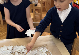 Chłopiec i dziewczynka przyklejają białe liście.