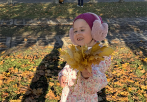 Dziewczynka trzyma w rączce bukiet z liści.