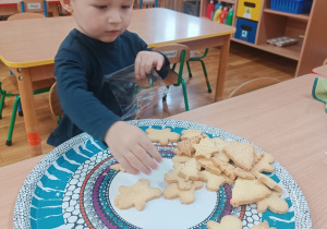 Chłopiec wkłada do woreczka ciastka.