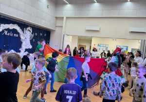 Dzieci przerzucają śnieżynki przez chustę animacyjną.