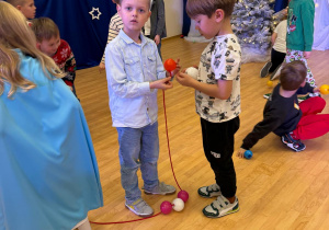 Chłopcy nawlekają bombki na łańcuch.