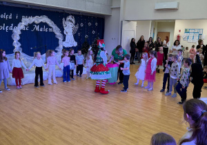 Dzieci stoją w kole z animatorem przebranym za elfa.