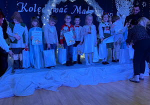 Uśmiechnięci uczestnicy na scenie z nagrodami.