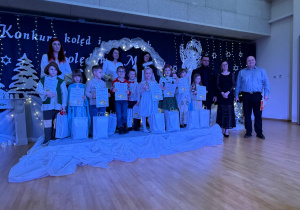 Uśmiechnięci uczestnicy na scenie z nagrodami.