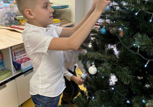 Chłopiec zawiesza bombkę.