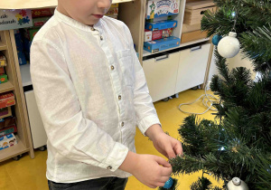 Chłopiec zawiesza bombkę.