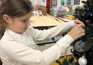 Dziewczynka przyozdabia choinkę.