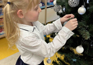 Dziewczynka przyozdabia choinkę.