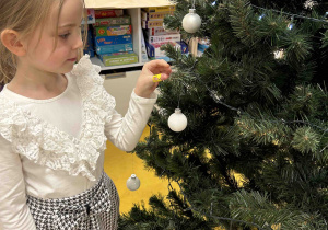 Dziewczynka zdobi choinkę.