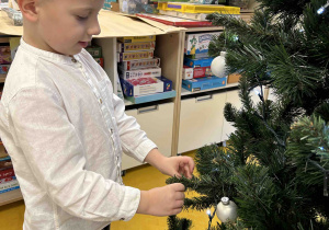 Chłopiec zawiesza bombkę.