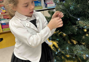 Dziewczynka zdobi choinkę.