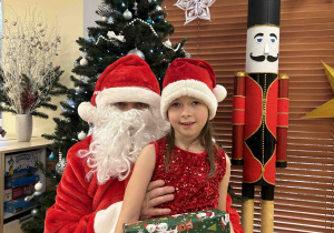 Dziewczynka pozuje do zdjęcia z Mikołajem.