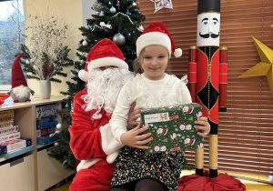 Dziewczynka pozuje do zdjęcia z Mikołajem.