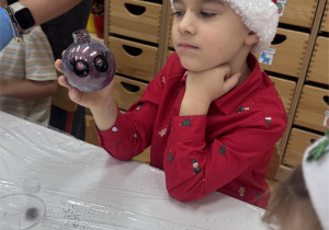 Chłopiec pokazuje bombkę z brokatem.