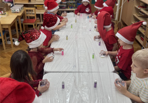 Dzieci siedzą przy stoliku i oczekują na rozpoczęcie pracy.