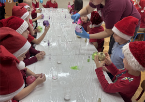 Dzieci wsypują brokat do bombek.