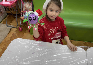 Dziewczynka prezentuje wytwór swojej pracy.