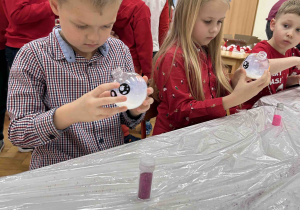 Dzieci przy stoliczkach ozdabiają bombki.