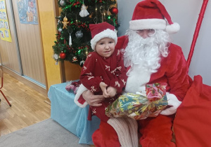 04. Dziewczynka siedzi na kolanach Świętego Mikołaja.