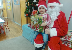 10. Chłopiec siedzi na kolanach Świętego Mikołaja.