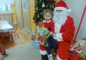 11. Dziewczynka siedzi na kolanach Świętego Mikołaja.