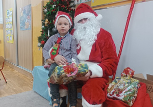 13. Chłopiec siedzi na kolanach Świętego Mikołaja.