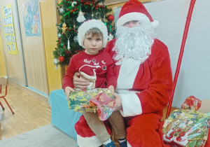 14. Chłopiec siedzi na kolanach Świętego Mikołaja.