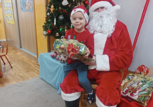 15. Chłopiec siedzi na kolanach Świętego Mikołaja.