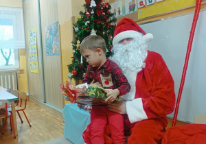 17. Chłopiec siedzi na kolanach Świętego Mikołaja.