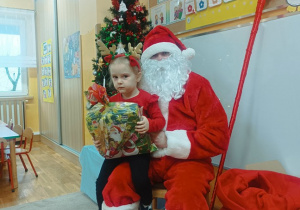 18. Dziewczynka siedzi na kolanach Świętego Mikołaja.