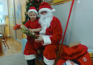 19. Chłopiec siedzi na kolanach Świętego Mikołaja.