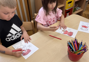 Dzieci siedzą przy stoliku i kolorują postać poznanego Czuciaka.