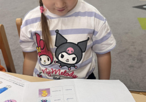 Dziewczynka siedzi a przed nią leży książeczka z Czuciakami.