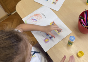 Dziewczynka wkleja postać Bojka do książeczki.