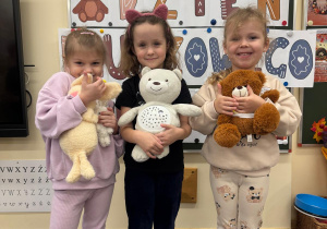 Dziewczynki pozują przytulone do misiów.