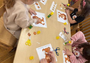 Dzieci układają puzzle z misiem.