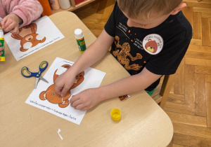 Chłopiec przykleja brakującą część misia.