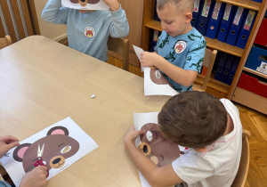 Chłopcy wycinają maskę misia.