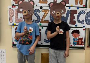 Chłopcy trzymają w ręku maski misia.