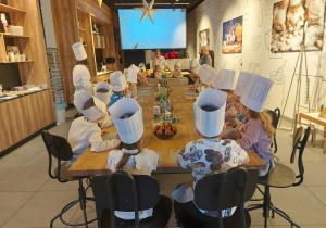 Dzieci siedzą i oglądają bajkę o chlebie.